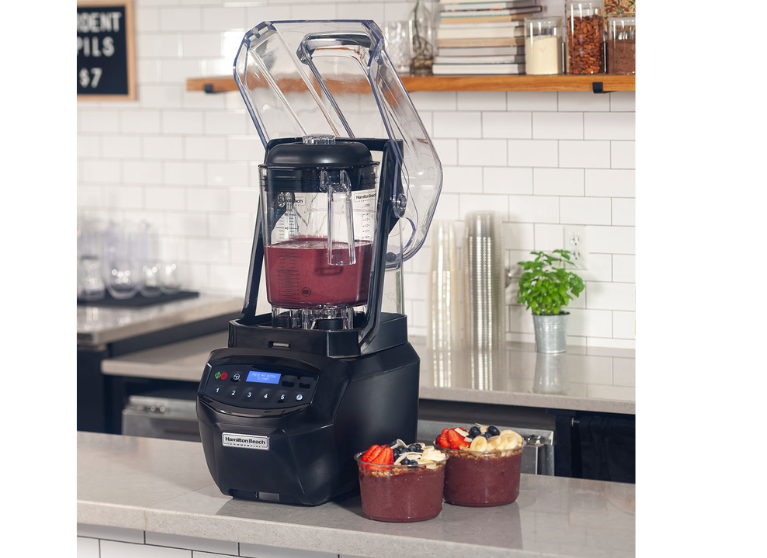 A blender full of smoothie mixture next to two smoothies